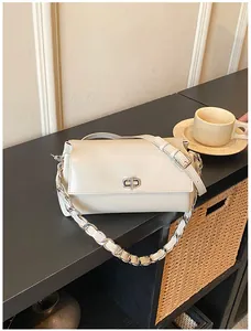 Détail du sac bandoulière en cuir crème avec fermoir tournant argenté et chaîne