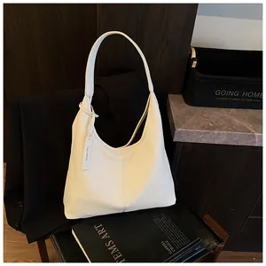 Vue détaillée du cabas blanc à texture litchi avec étiquette sur un blazer noir
