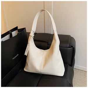 Détail du sac cabas en cuir texturé blanc cassé avec couture et étiquette de marque