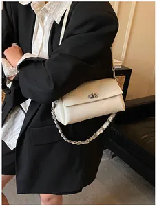 Détail du sac rectangulaire blanc crème avec fermoir rotatif argenté et chaîne en métal