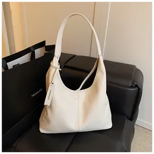 Détail du sac hobo en cuir grainé crème sur un fond de canapé en cuir noir élégant