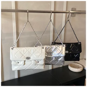 Three quilted chain bags in white, silver, and black hanging on a metal display stand