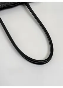 Détail des poignées d'un sac cabas en cuir tressé noir avec coutures de précision