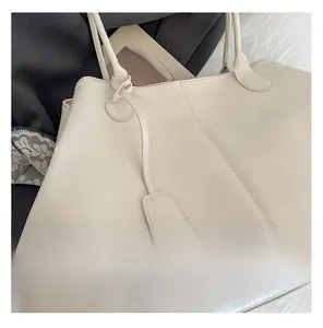 Detailed close-up of cream leather tote bag featuring refined stitching and hanging tag