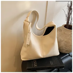 Détail du cuir grainé et étiquette logo embossée sur le sac cabas beige