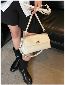 Détail du sac bandoulière en cuir blanc crème avec serrure argentée et sangle à chaîne
