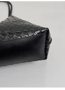Vue détaillée du fond renforcé et de la texture en cuir tressé du sac cabas noir