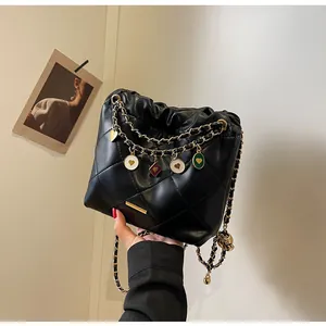 Détail du sac seau matelassé noir avec chaîne dorée et breloques de cœur émaillées