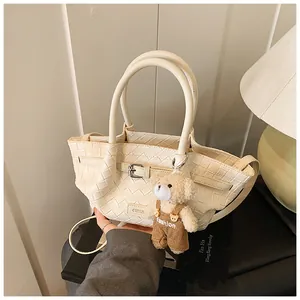 Gros plan du sac seau tissé blanc cassé avec un charmant pendentif en forme d'ours peluche