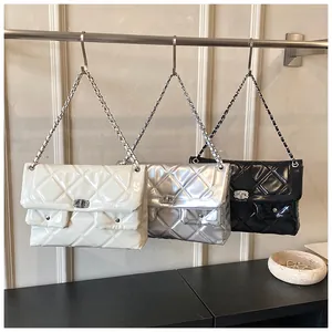 Close-up of quilted leather bags in white, silver, and black with metal chain straps