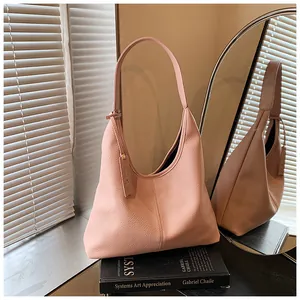 Gros plan du sac cabas rose grainé posé sur un livre avec une lumière naturelle douce