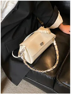 Détail du sac à main en cuir crème avec fermoir rotatif argenté et bandoulière en chaîne
