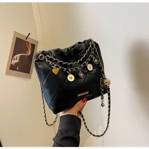 Détail du sac seau noir matelassé avec chaîne dorée et breloques émaillées colorées