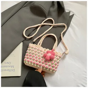Detailed view of handmade crochet shoulder bag with pink tulip patterns and 3D floral charm