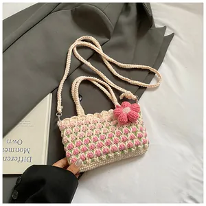 Detail of crochet tulip bucket bag featuring a pink 3D flower charm and pearl button