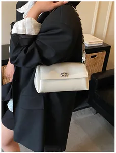 Détail du sac sous l'aisselle blanc crème avec fermoir rotatif argenté et bandoulière