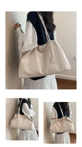 Detail view of large cream tote bag with soft faux leather texture and minimalist tag