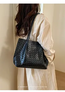 Détail du cabas tressé noir avec texture sophistiquée et fines bretelles de luxe