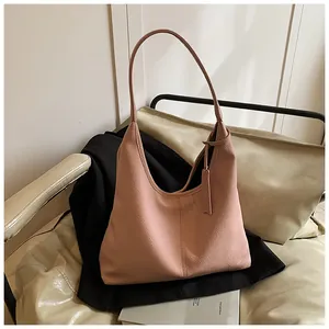 Détail du sac hobo rose en cuir grainé montrant la texture souple et la bandoulière fine