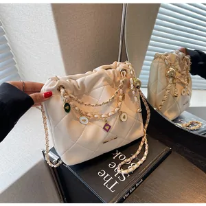 Détail du sac seau blanc matelassé avec chaîne dorée et breloques en cœur
