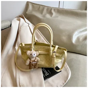 Détail du sac seau tissé jaune avec breloque ours en peluche et bandoulière réglable