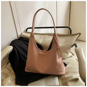 Détail du sac cabas en cuir rose grainé avec bandoulière nouée sur une chaise chic
