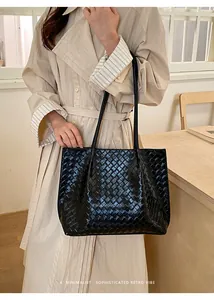 Détail macro du motif tressé intrecciato sur un sac cabas noir en cuir synthétique chic