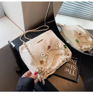 Détail du sac seau matelassé beige avec pendentifs en forme de cœur et bandoulière