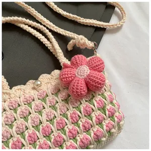Close-up of handmade crochet bag featuring pink tulip patterns and pearl button closure