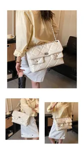 Detail of white quilted crossbody bag with metal twist lock and chain strap on model
