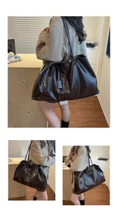 Detail of a large brown glossy tote bag showing high-shine leather and slim shoulder straps