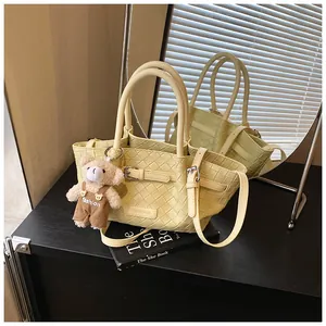 Détail du sac seau tissé jaune clair avec bandoulière et charmant ours en peluche