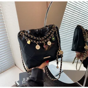 Détail du sac seau noir matelassé avec chaînes dorées et breloques colorées en émail
