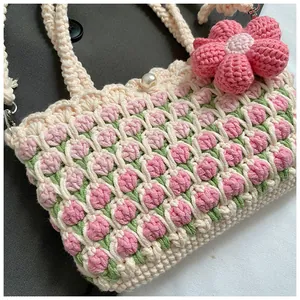 Detailed view of hand-woven tulip patterns and a pearl closure on a beige crochet bag