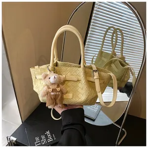 Détail du sac seau tissé jaune clair avec breloque ours en peluche et boucle métal