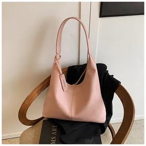 Détail du sac cabas rose en cuir grainé sur une chaise avec livre de mode et bandoulière