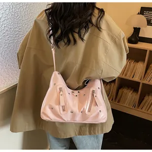 Detail der rosa Lackledertasche im Y2K-Stil mit silbernen Nieten und Metall-Logo-Plakette