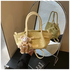 Détail du sac seau tissé jaune clair avec un charmant ours en peluche sur un bureau