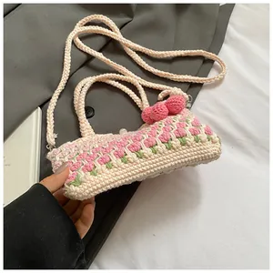 Detail of hand-woven tulip crochet bucket bag with pink cherry charms and long shoulder strap