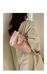 Detail of soft light pink tote bag featuring a decorative belt buckle and plush bear charm