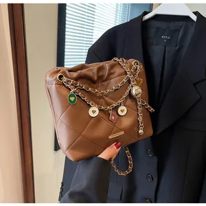 Gros plan du sac seau matelassé marron avec chaîne dorée et pendentifs décoratifs