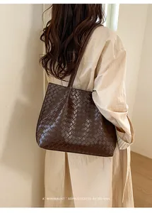 Détail d'un grand sac cabas tressé marron foncé avec texture en cuir et design élégant