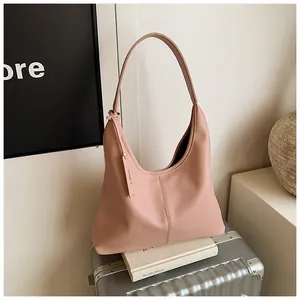 Détail du sac cabas rose avec texture grainée posé sur une valise pour le voyage