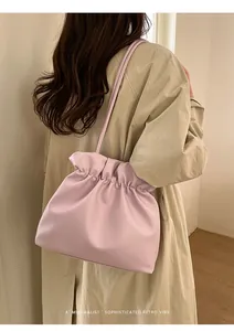 Chic pink bucket bag with soft pleats shown on model with beige trench coat