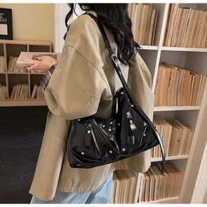 Detail der schwarzen Lackleder-Schultertasche mit silbernen Nieten und Reißverschluss