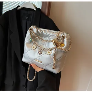 Détail du sac seau matelassé argenté avec chaîne et pendentifs en forme de cœur