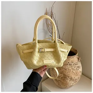 Détail du sac seau en cuir tressé jaune avec poignée et plaque de la marque CHERIMATE