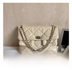 Detail of beige quilted chain bag featuring turn-lock closure and leather woven straps
