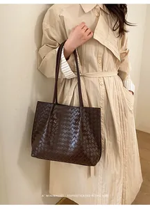 Détail de la texture en cuir tressé marron foncé sur un sac cabas rétro minimaliste