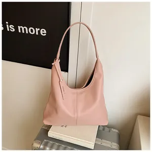 Détail de la texture cuir litchi rose et étiquette de marque sur un sac hobo moderne